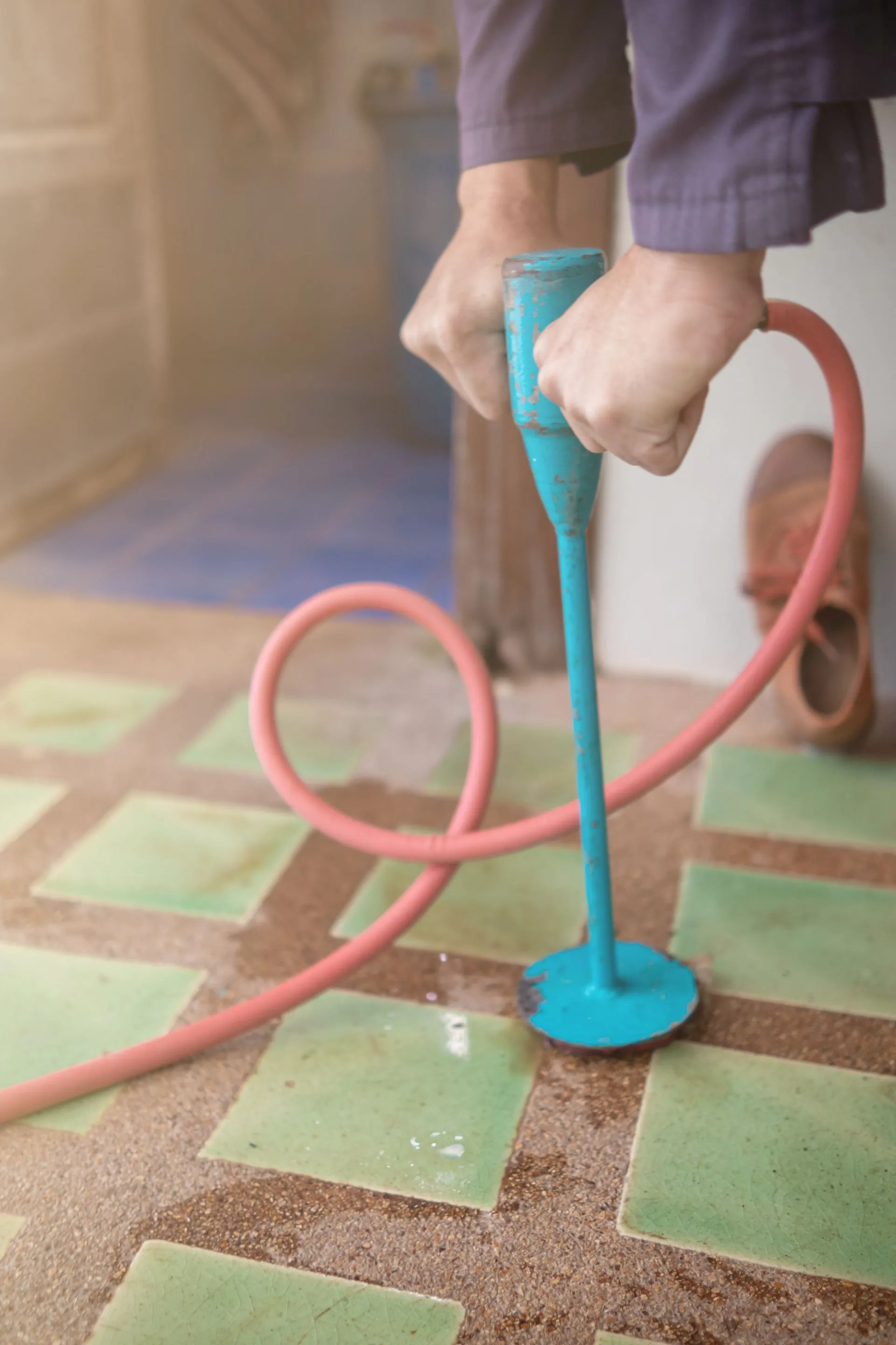 A person is holding a blue object with a pink hose attached to it. A person is holding a blue object with a pink hose attached to it.